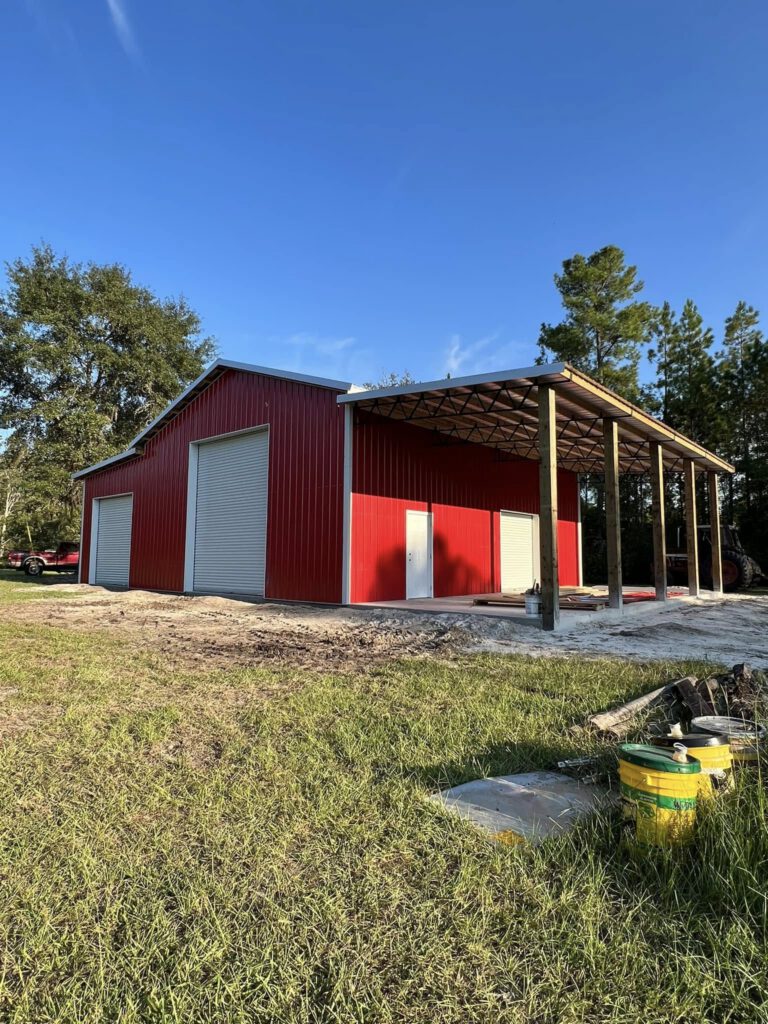 Red pole barn with white trim and garage doors